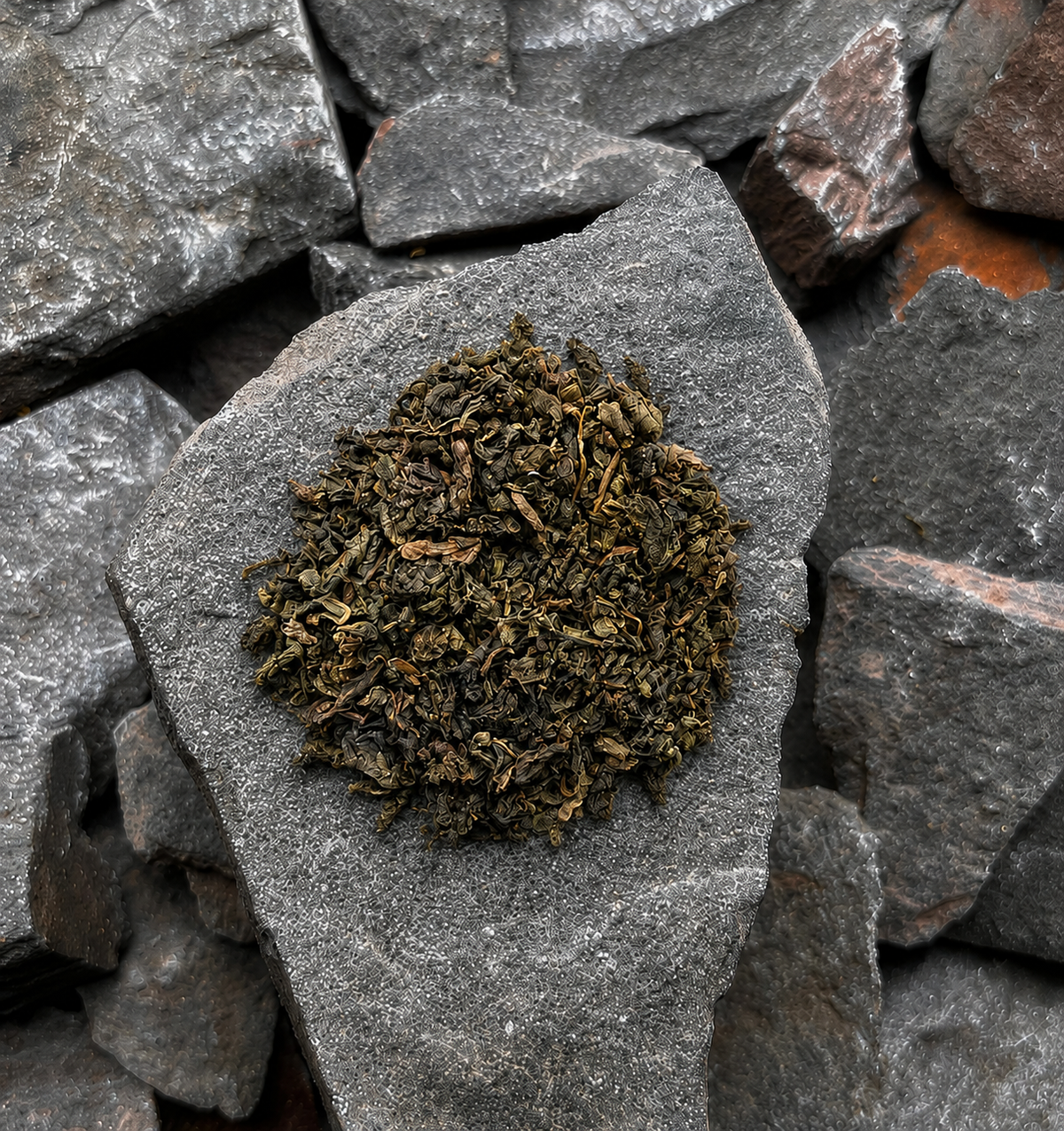 Green Oolong loose-leaf tea leaves sits on a smooth grey slate