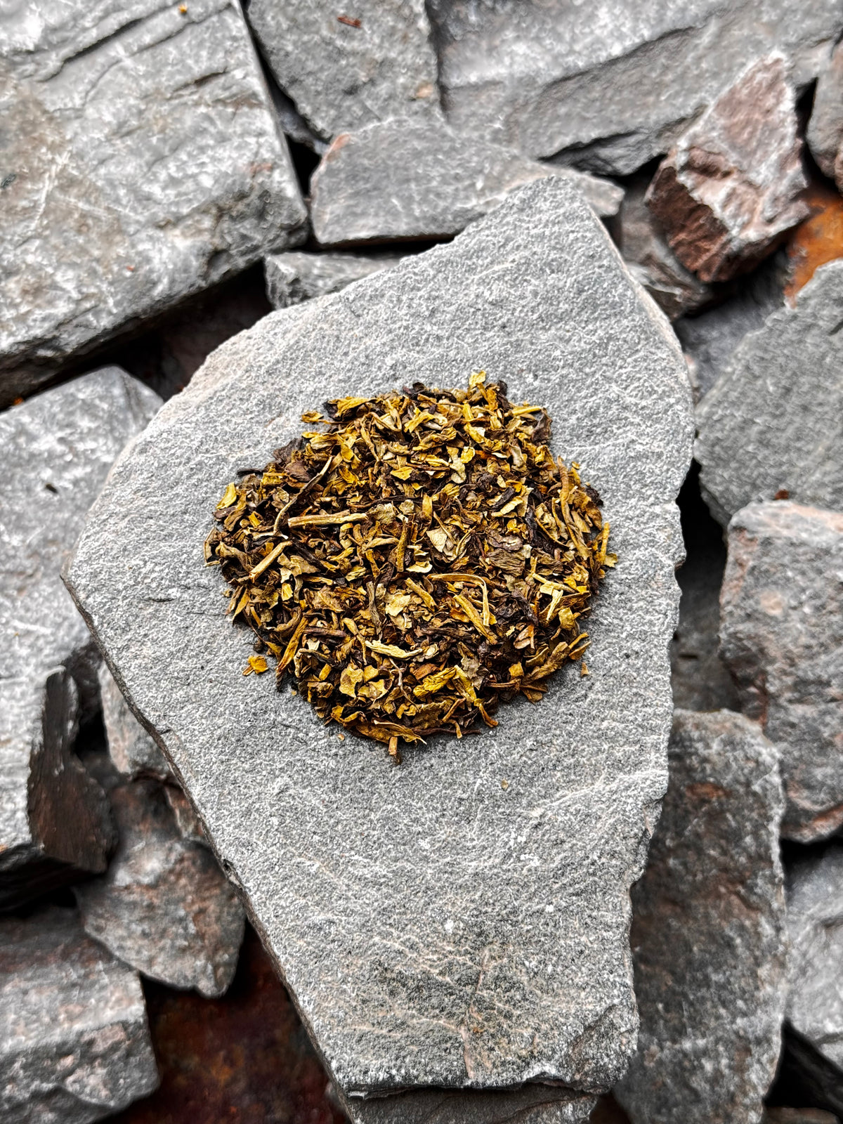 Decaf Green Sencha Kyushu loose leaf tea, showing fine green and golden leaves arranged on a grey slate stone  at high summit tea co